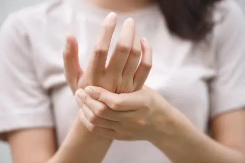 Mains tenant une main, évoquant le fourmillement et les symptômes de la maladie de Charcot.