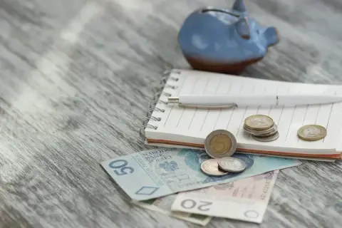 Niebieskana świnka-skarbonka, notatnik, długopis i polskie pieniądze. Planowanie wydatków, może na zasiłek okresowy?
