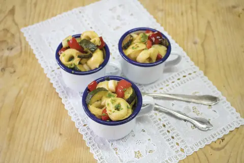 Drei Tassen mit Tortellini-Salat, garniert mit frischen Kräutern. Perfekt für die **10 besten Salate** zum Sommerfest.