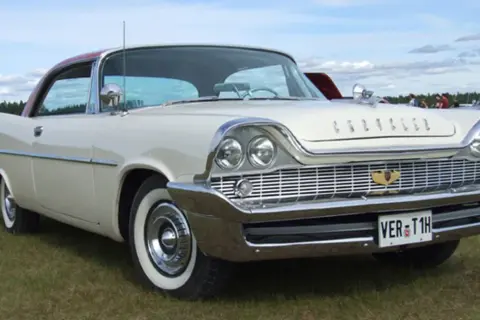 Vit Chrysler 58 med rött tak, blanka kromdetaljer och vit sidovägg på däcken. Bilen står på en gräsmatta.