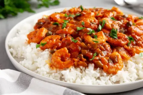 Garnelen in Tomatensauce mit Reis, eine schnelle Sauce zu Fisch und Reis, garniert mit Petersilie.