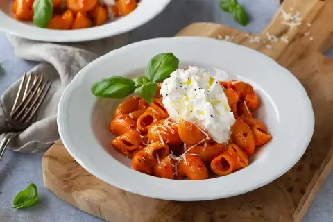 Krämig nduja pasta med burrata och färsk basilika, serverad på en vit tallrik.