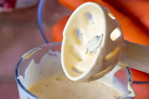 Batidora de inmersión con mayonesa casera cremosa, lista para acompañar unas zanahorias frescas.