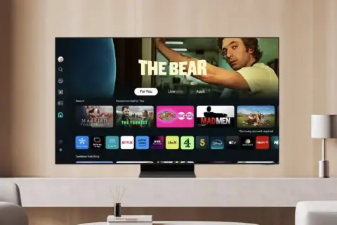 Telewizor z systemem Tizen wyświetla menu z popularnymi serialami i aplikacjami, takimi jak "The Bear", Netflix i Prime Video.