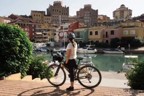 Ciclista en un puerto con casas de colores y barcos. Perfecta para descubrir las **rutas bici Valencia**.