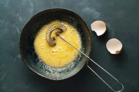 Ubite żółtka w misce, obok skorupki jajek. Idealne do omletu lub ciasta.