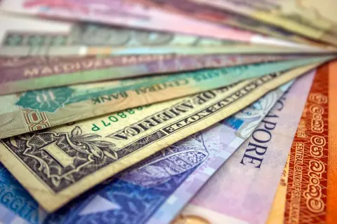 Różne waluty świata ułożone wachlarzowo, od dolara amerykańskiego po banknoty z Singapuru i Sri Lanki. Ile jest walut na świecie? Tyle, ile widzisz tutaj i jeszcze więcej!