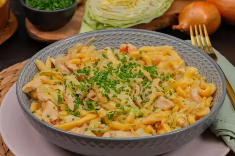 Herzhafte Spätzle mit Hähnchen und Spitzkohl, garniert mit Schnittlauch. Ein leckeres Gericht, das zeigt, wie vielseitig Spitzkohl Rezepte sein können.