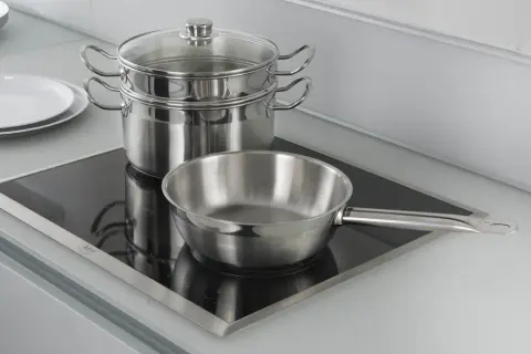 Pentole e padelle in acciaio inox pronte per cucinare su piastra a induzione.