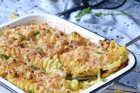 Gratin de pâtes au poulet et à la béchamel, doré et gratiné, garni de persil frais.