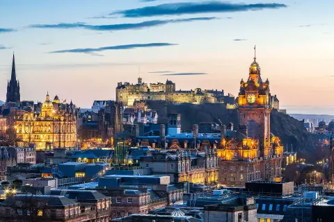 Edinburgh im Oktober: Die beleuchtete Skyline mit dem Schloss und dem Scott Monument im Abendlicht.