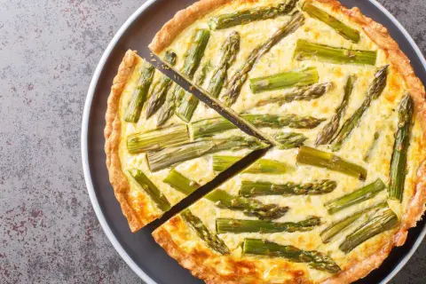 Eine köstliche Spargel Quiche mit einem goldbraunen Teigrand und saftiger Füllung, belegt mit frischem Spargel.