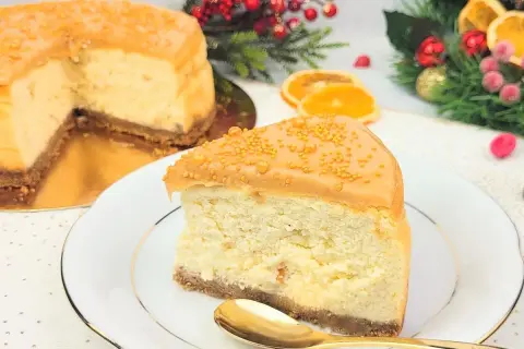 Pyszny sernik z ciasteczkami korzennymi, udekorowany karmelem i złotymi kuleczkami. Idealny na święta!