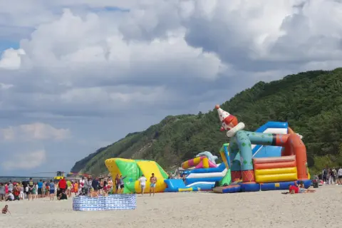 Kolorowe dmuchańce na plaży w Międzyzdrojach to świetne atrakcje dla dzieci. Wesoły klaun zaprasza do zabawy.