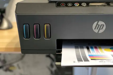 Drukarka HP z kolorowymi wskaźnikami tuszu, drukująca stronę testową. Dowiedz się, jak wydrukować z telefonu na drukarce HP.