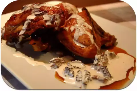Pollo dorado bañado en una cremosa salsa de colmenillas, con trozos de hongo visibles.