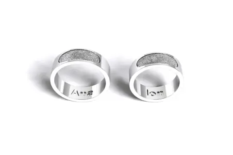 Dos anillos de plata grabados con huellas dactilares y nombres: "Ana" y "Ian". Un símbolo de amor eterno para rodear el dedo.