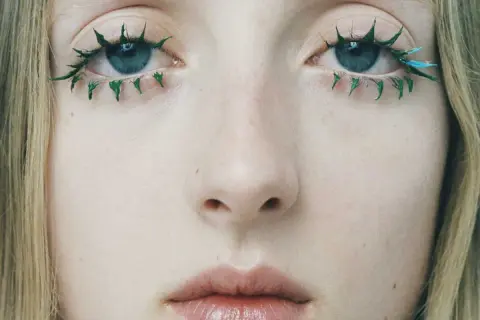 Yeux bleus aux cils verts et bleus, comme un mascara yeux qui pleurent artistiquement appliqué.