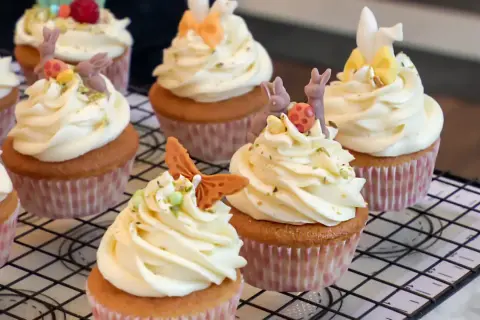 Zarte Vanille Cupcakes mit cremiger Glasur, verziert mit süßen Osterhasen und bunten Eiern. Ein Fest für die Augen und den Gaumen!