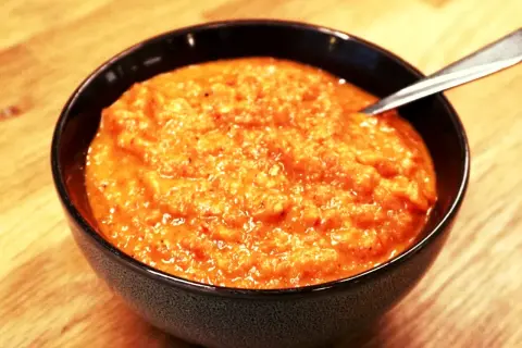 En skål med krämig ajvar, perfekt för ditt ajvar recept. En sked vilar i den orangea röra.