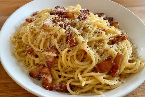 En krämig carbonara med pancetta, toppad med riven ost och svartpeppar. En klassisk italiensk rätt som ser utsökt ut.