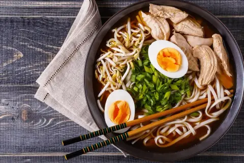 Misja: odkryć, czym jest ramen. Na talerzu paruje aromatyczny bulion z kurczakiem, jajkiem, kiełkami i szczypiorkiem.