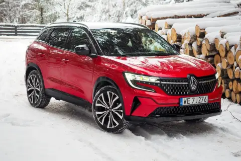 Czerwony Renault Austral na śniegu, z widocznymi felgami i grillem. Poznaj jego wymiary i możliwości w zimowych warunkach.