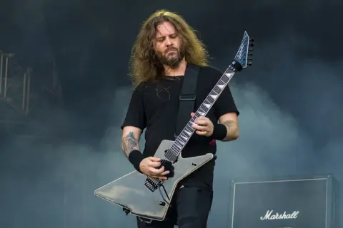 Charyzmatyczny gitarzysta rockowy z długimi włosami, grający na czarnej gitarze typu explorer. Jeden z wielu utalentowanych polskich gitarzystów rockowych.