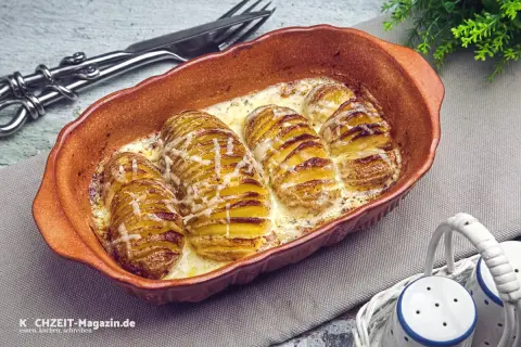 Gerichte mit Kartoffeln: Hasselback-Kartoffeln in cremiger Sauce, goldbraun gebacken und mit Käse überbacken, serviert in einer Terrine.