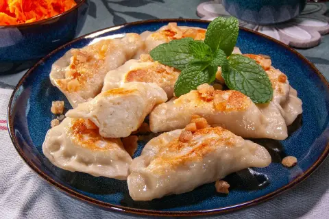 Pyszne pierogi ruskie przepis babci, okraszone skwarkami i udekorowane miętą.