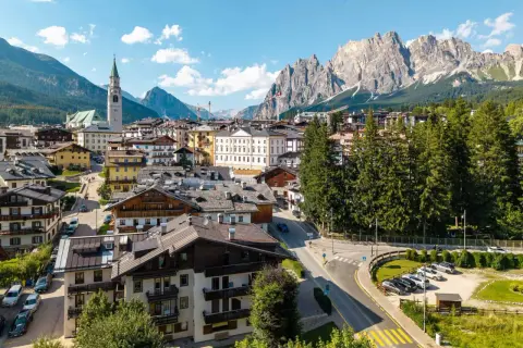 Vue d'un village pittoresque niché au pied des Dolomites en Italie, avec des maisons traditionnelles et une église imposante.