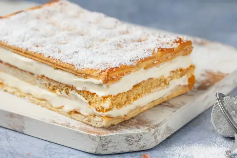 Una deliziosa torta diplomatica, stratificata con soffice crema e sfoglia croccante, spolverata di zucchero a velo.