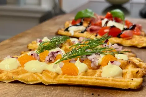 Matiga våfflor med rom, dill, rödlök och majonnäs. En annan våffla i bakgrunden med tomat, mozzarella och basilika.