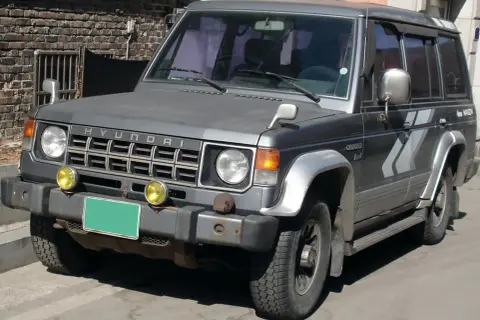 Szary Hyundai Galloper 2.5 TDI z żółtymi światłami przeciwmgielnymi i zieloną tablicą rejestracyjną.
