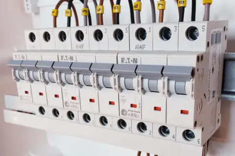 Rzędy bezpieczników w rozdzielnicy elektrycznej, różne rodzaje bezpieczników i ich oznaczenia.