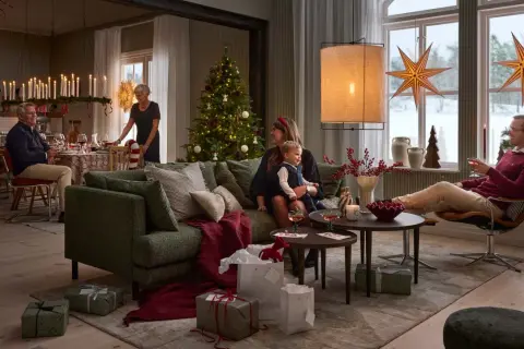 En familj samlas för en mysig jul. Julgranen är klädd, presenter ligger utspridda och ljusen lyser upp rummet.