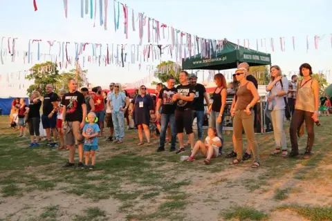 Ludzie na festiwalu trzcianka, w tle kolorowe wstążki i namioty.