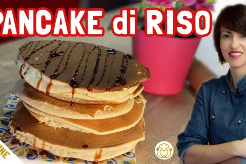 Pancake di riso senza glutine, una pila golosa con sciroppo al cioccolato. Una donna sorride sullo sfondo.