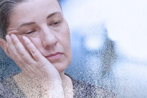 Zmęczona kobieta z dłonią na policzku, symbolizująca mgłę covidową i długotrwałe skutki choroby.