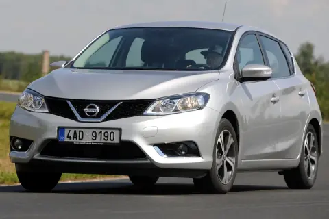 Srebrny Nissan Pulsar w ruchu drogowym. Kierowca w kapeluszu za kierownicą. Wiele pozytywnych nissan pulsar opinie.