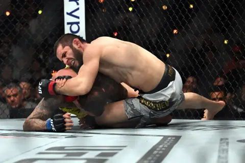 Två MMA-fighters i en intensiv kamp på mattan under UFC 311. En kämpe har överhanden och försöker säkra en submission.