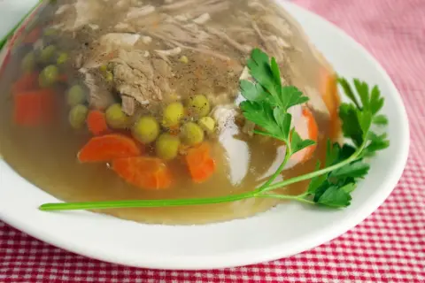 Galareta z mięsem, marchewką i groszkiem, udekorowana natką pietruszki. Idealna proporcja, by wiedzieć, ile żelatyny na 1 litr rosołu.