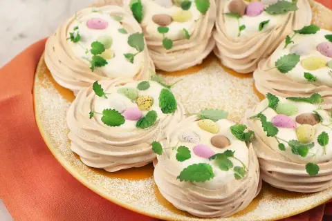 Små marängbottnar fyllda med grädde och dekorerade med färgglada påskägg och mynta. En perfekt pavlova påsk-dessert!