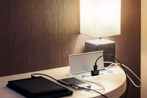 Elegancka ładowarka z gniazdkami i portami USB, idealna do tego, jak ukryć kable. Obok leżą tablet i smartfon.