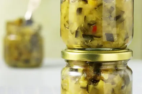 Zwei Gläser mit selbstgemachtem Zucchini-Chutney, eines auf dem anderen gestapelt.