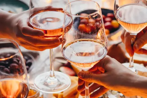 Różowe wino w kieliszkach, czy po butelce wina można już mówić o promilach? Przyjemny wieczór z przyjaciółmi.