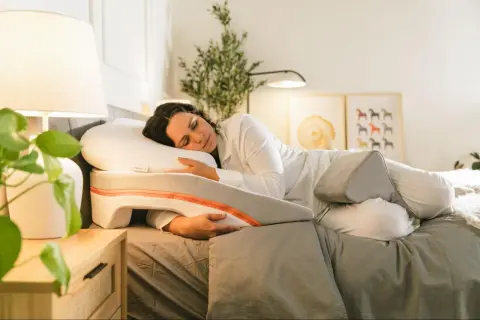 Woman sleeping peacefully on a specialized pillow designed to help with snoring. This pillow offers support for a comfortable sleep position, showing como poner la almohada para no roncar.