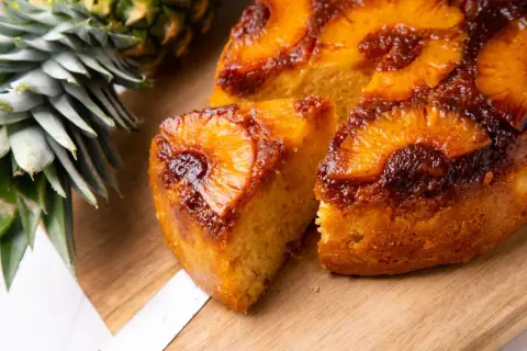 Pyszne, karmelizowane ciasto z patelni z kawałkami ananasa, obok świeży ananas.