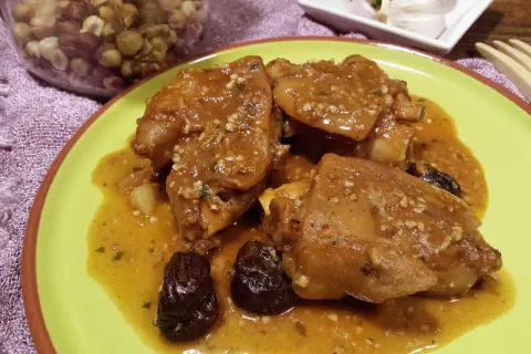 Pies de cerdo a la catalana, un plato tradicional con trozos de cerdo en una salsa dorada, acompañado de ciruelas pasas.
