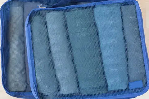 Två blå packpåsar med rullade kläder. Ett perfekt **pile material** för organiserad packning.